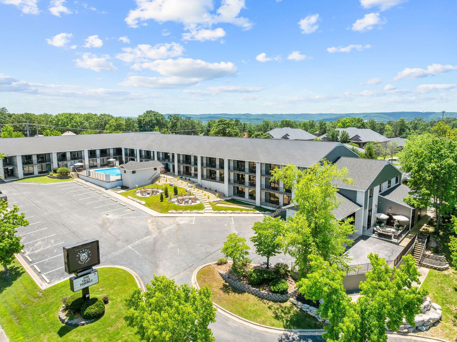 An aerial view of a hotel surrounded by trees and a parking lot.