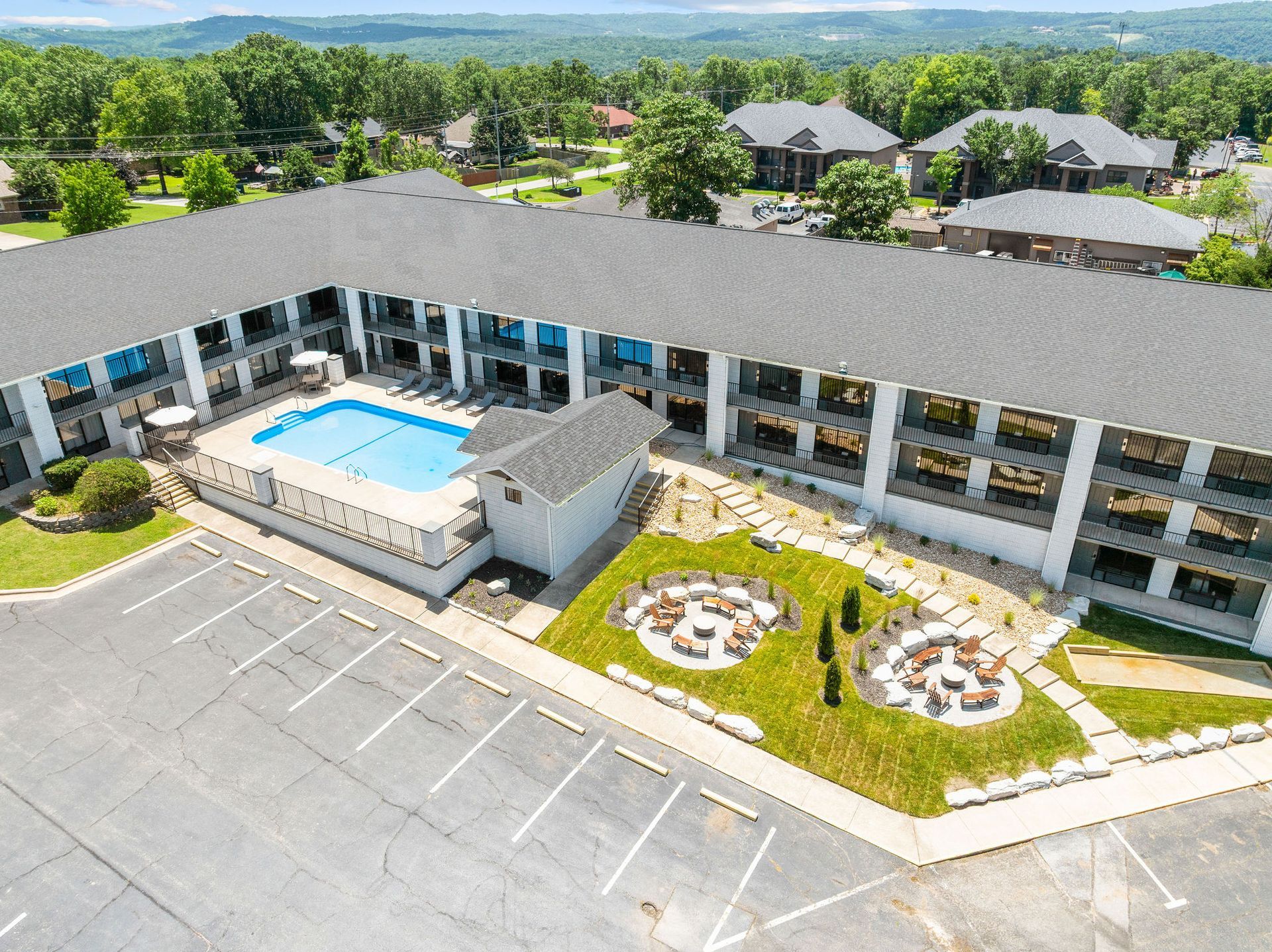 An aerial view of a hotel with a swimming pool and a parking lot.