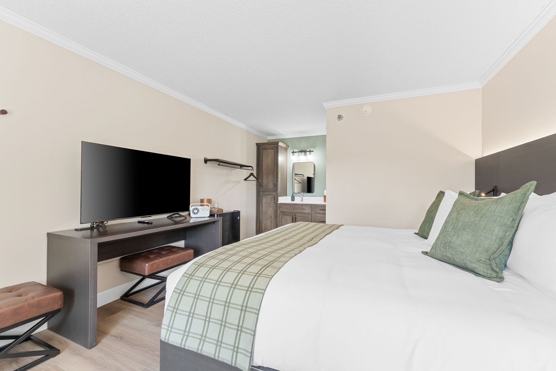 A hotel room with a king size bed , desk , television and bathroom.