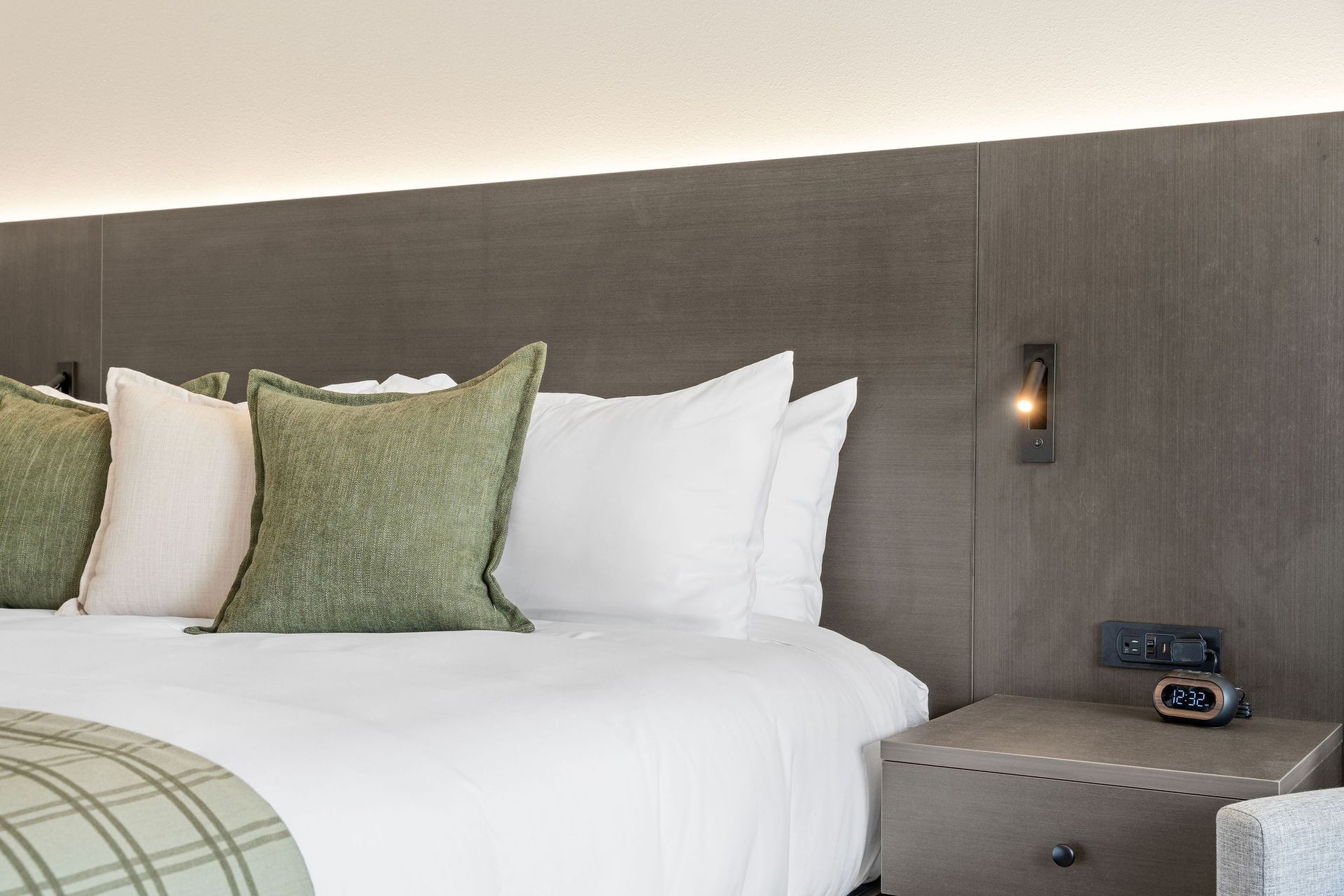 A hotel room with a bed , nightstand , and clock.