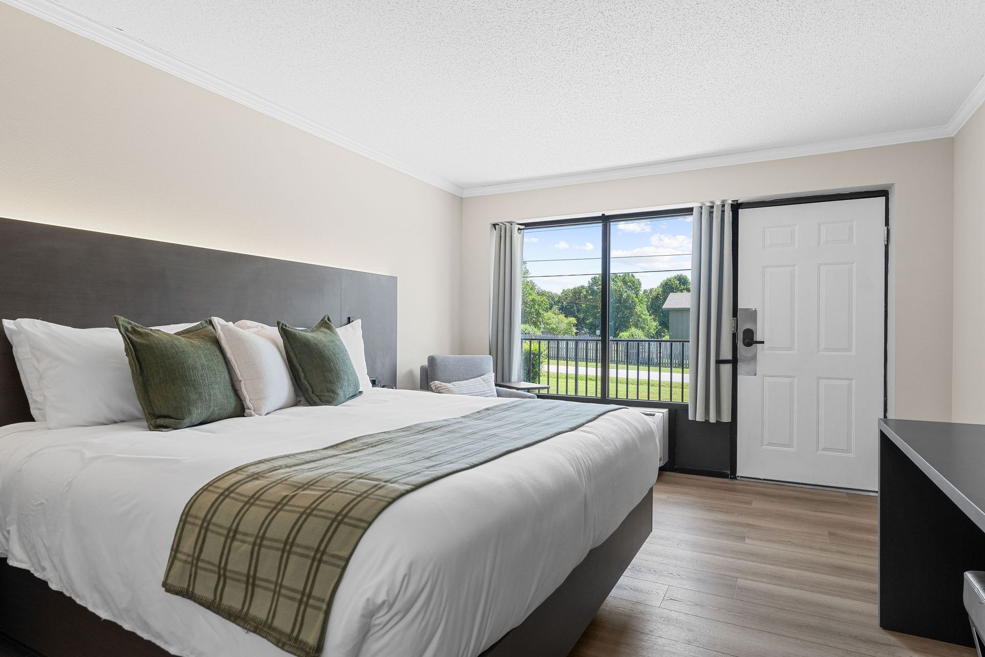 A hotel room with a king size bed and a large window.