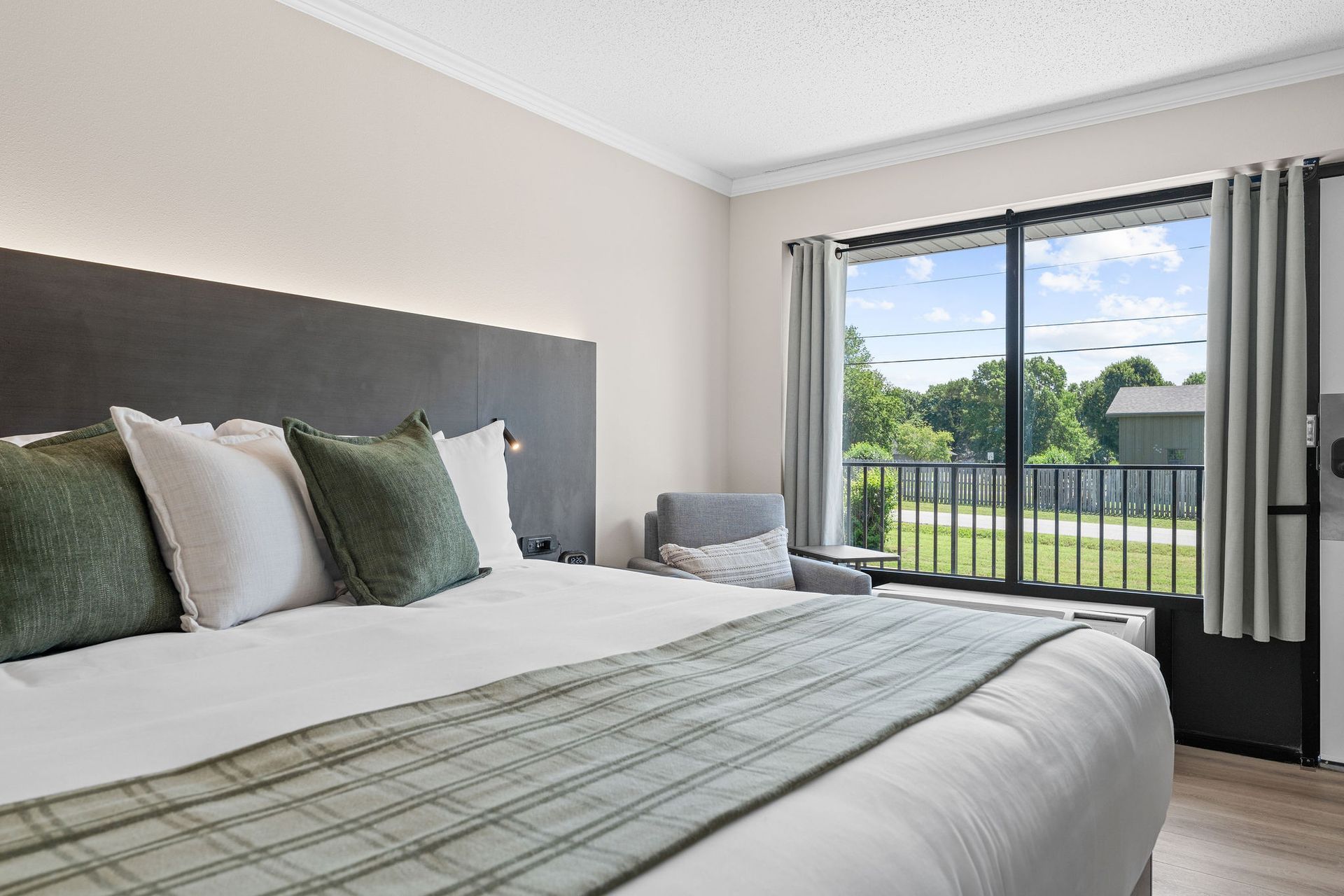 A hotel room with a king size bed and a sliding glass door.