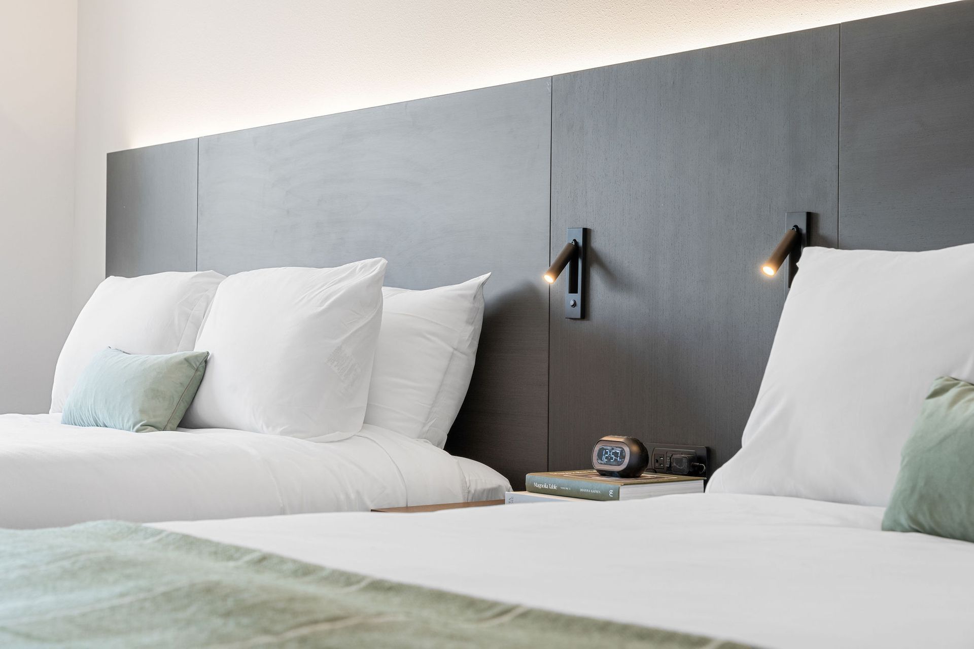 A hotel room with two beds and a clock on the nightstand.