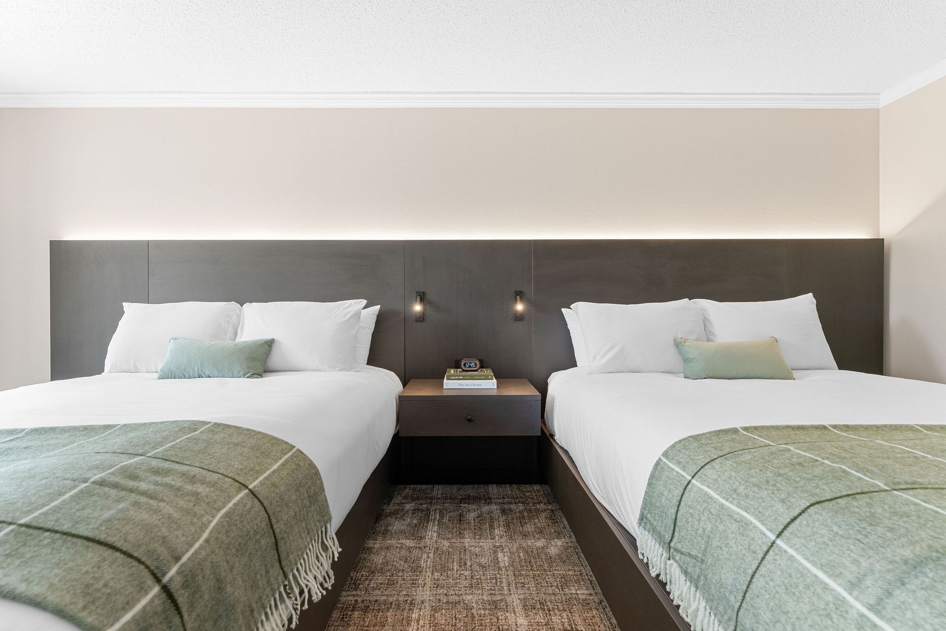 A hotel room with two beds and a nightstand.