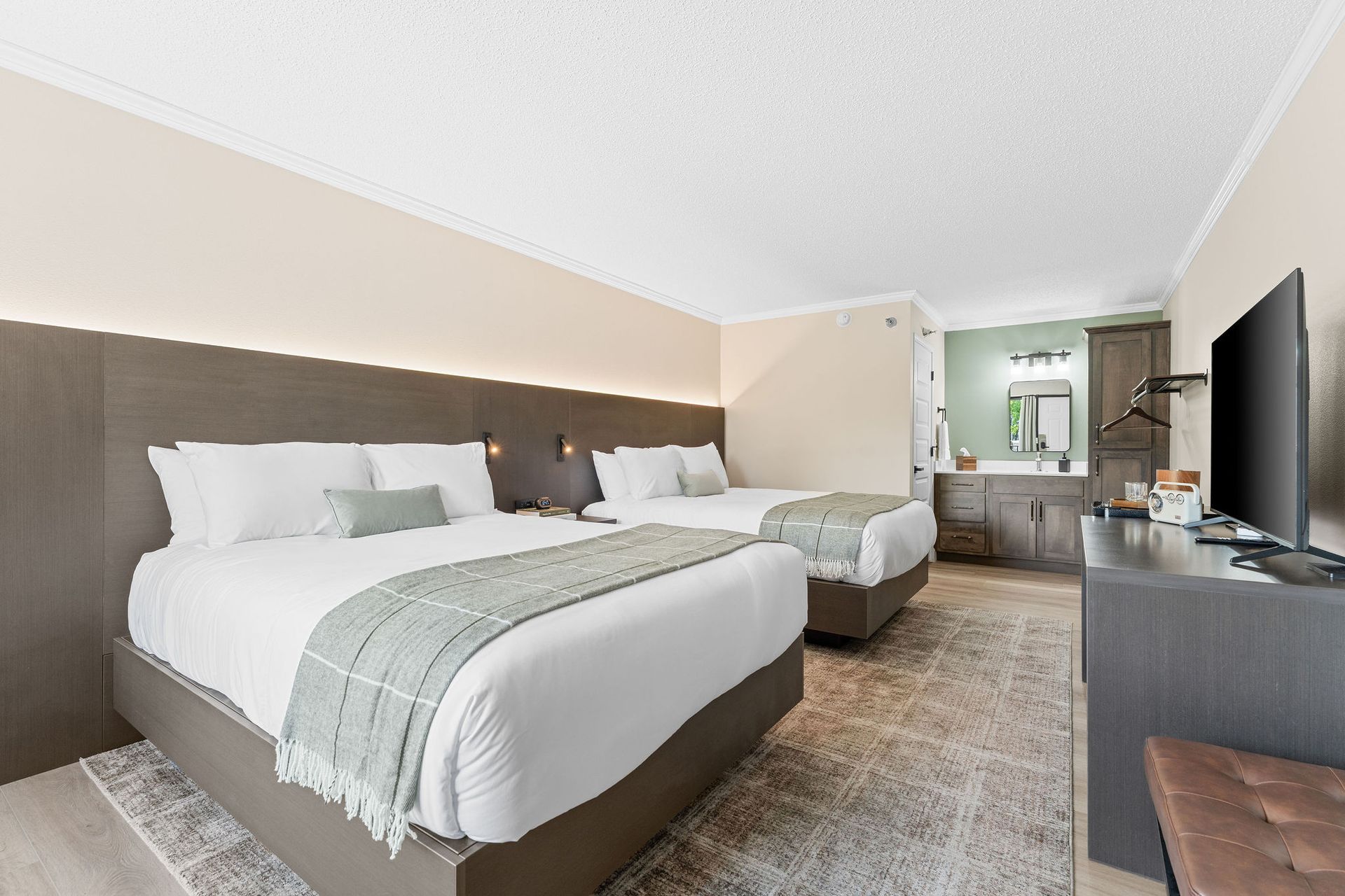 A hotel room with two beds and a flat screen tv.