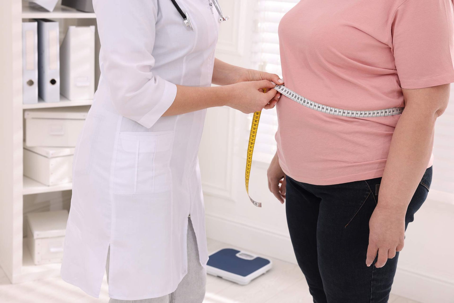 Nutritionist measuring waist of overweight woman at weight loss clinic.