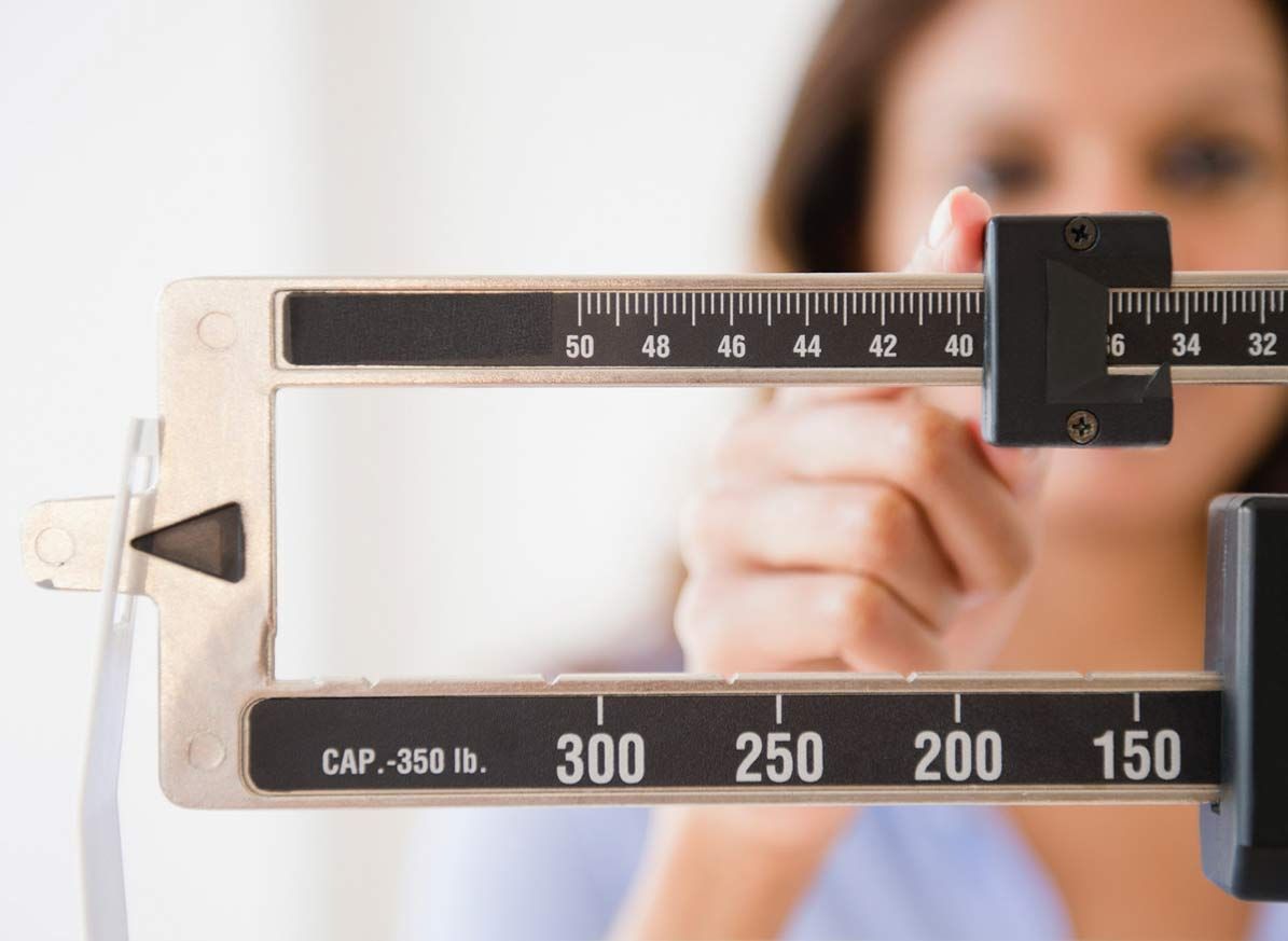 Woman checking weight on scale at weight loss clinic, focused on health and wellness.