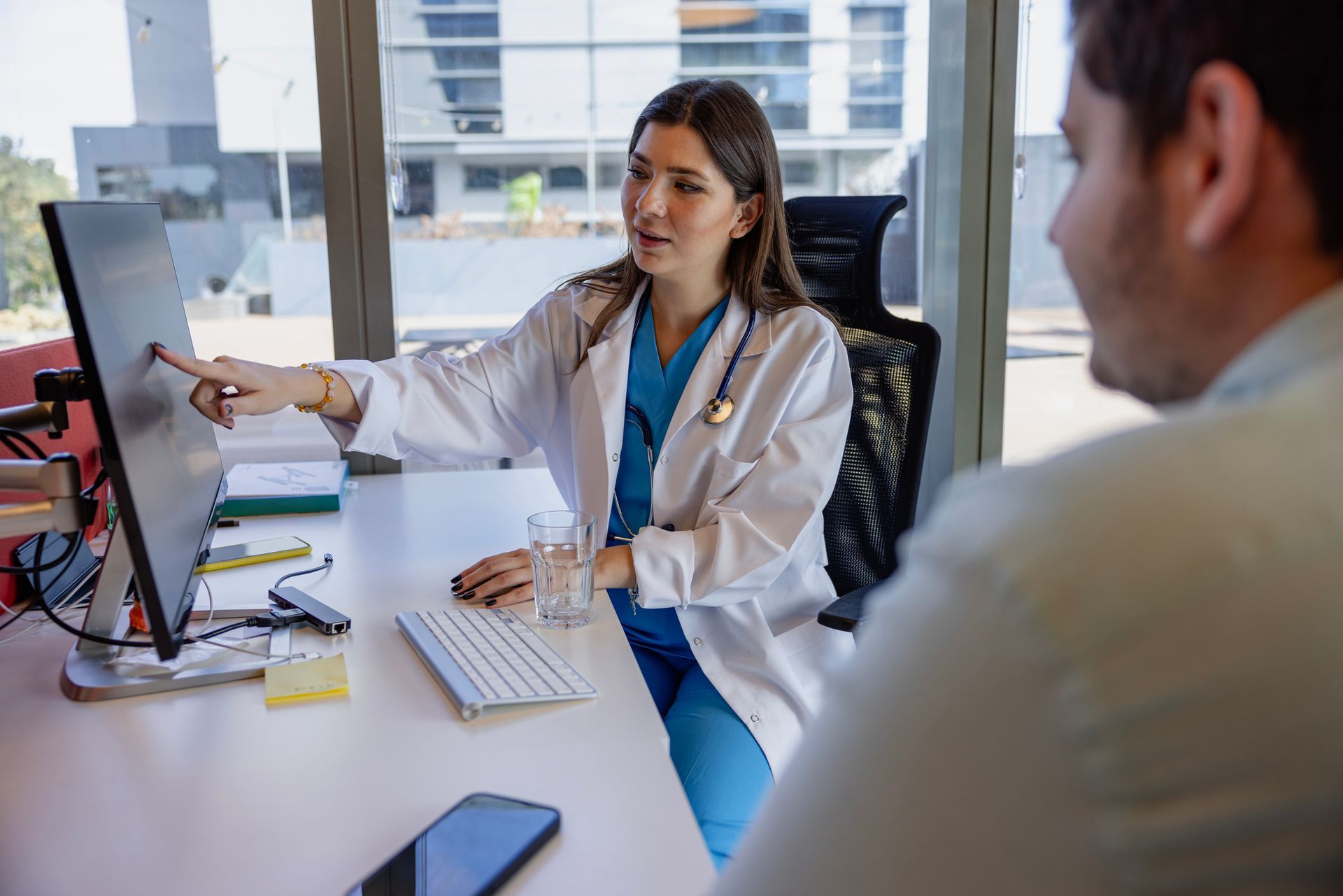 Doctor explaining medical weight loss services to patient using computer screen in modern office.