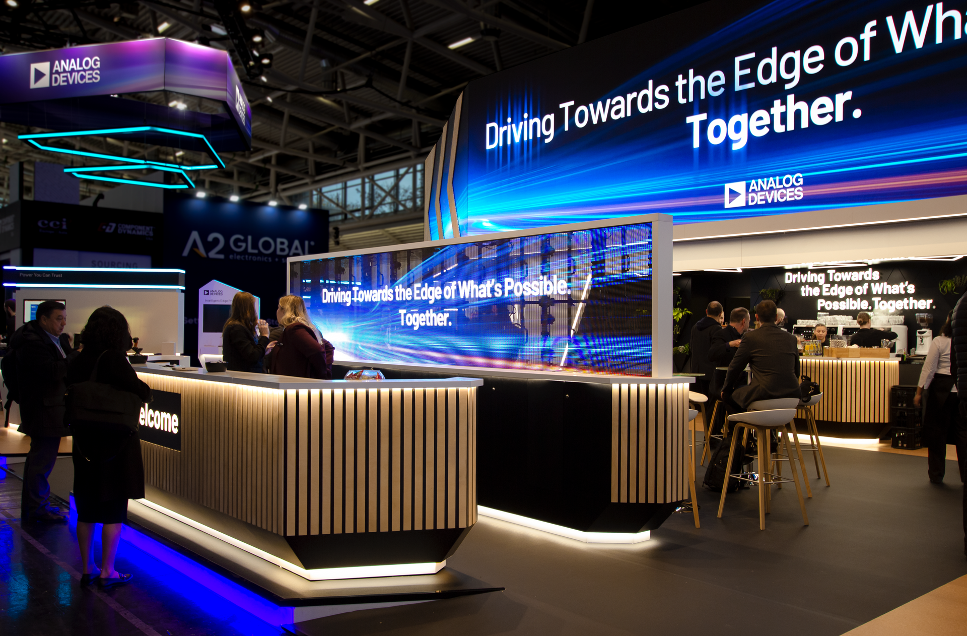 The Analog Devices booth at Electronica 2024, featuring an LED wall, cork flooring and product demonstration areas.