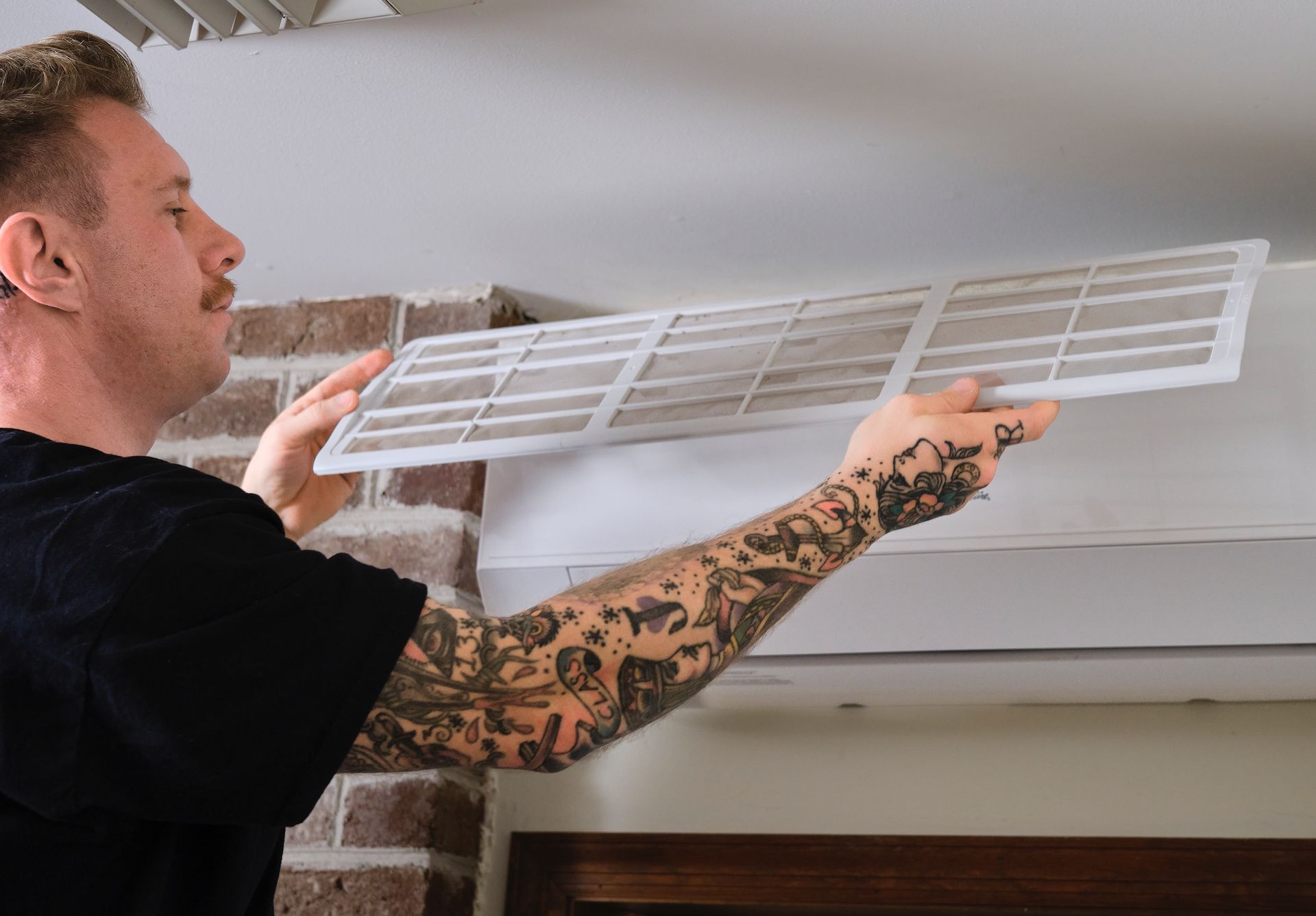 Electrician in yellow hard hat working on wiring inside a wall.