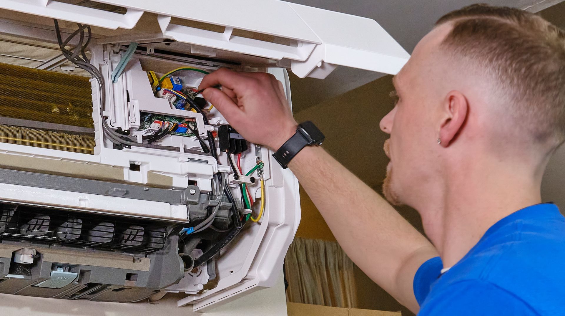 Electrician working on a circuit breaker panel in a residential setting.
