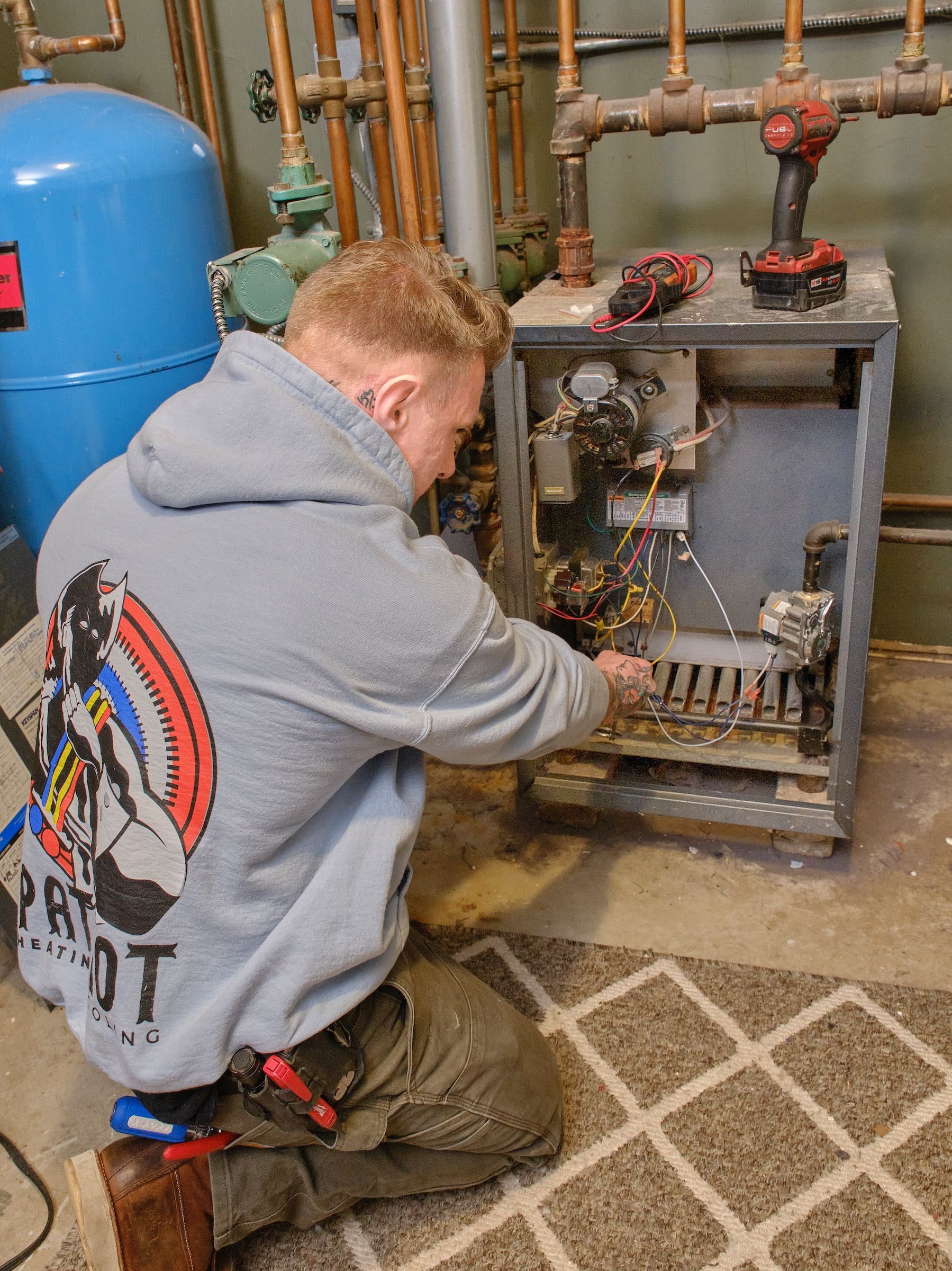 Electrician in yellow hard hat working on wiring inside a wall.