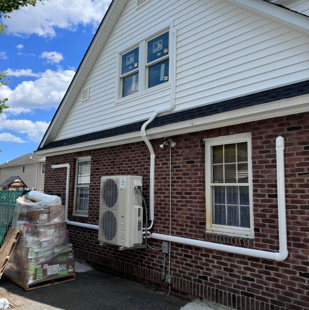 Brick house with white siding and air conditioning unit installed on the wall with white pipes.