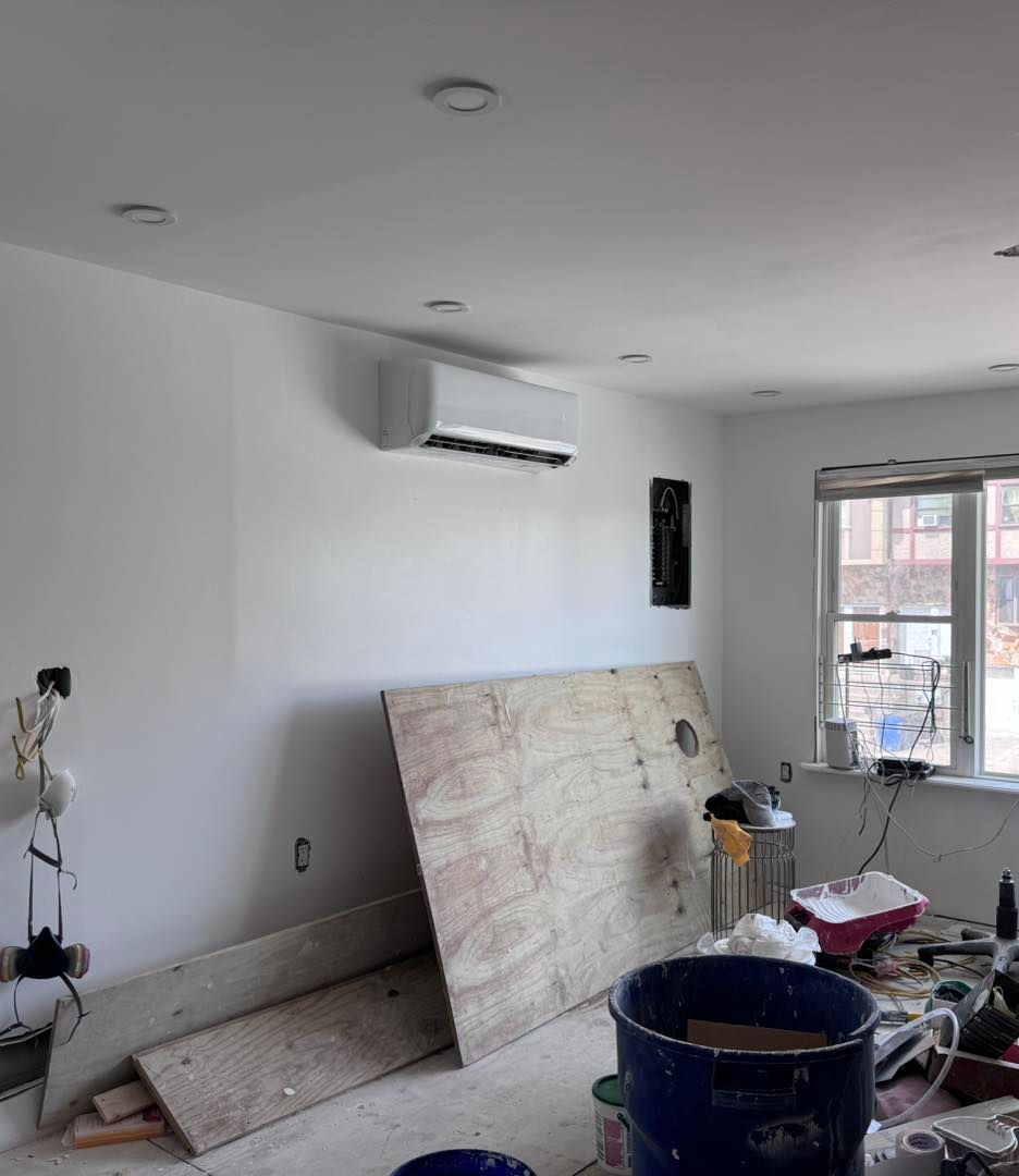 Interior room under renovation with air conditioner, plywood, and debris.