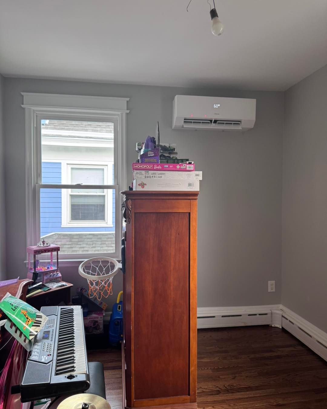 Bedroom with a window, tall wooden dresser, toys, and an air conditioning unit.