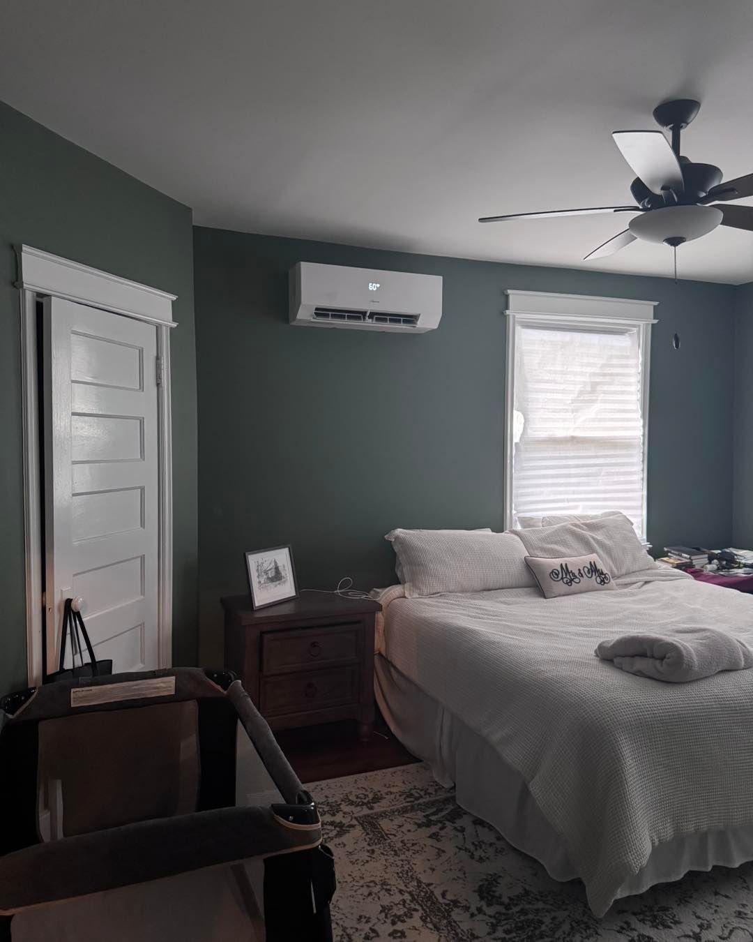 Bedroom with green walls, a bed, air conditioning unit, door, window, nightstand, and ceiling fan.