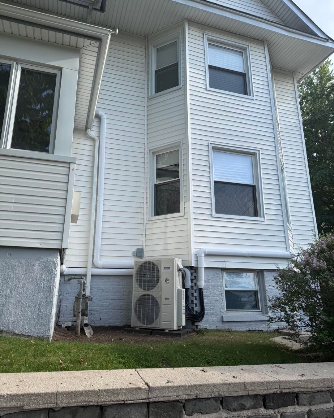 White house exterior with air conditioning unit on the ground.