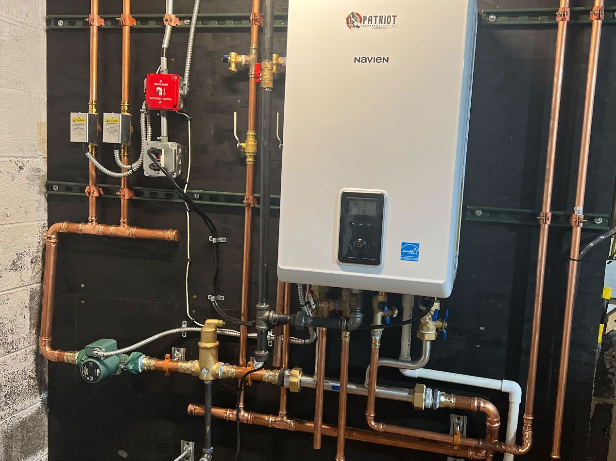 Copper pipes and a white water heater mounted on a black wall with electrical components.
