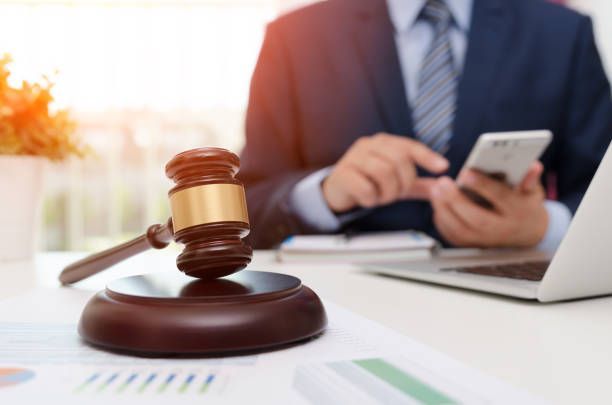 Judge gavel on legal documents with business professional using smartphone and laptop in law office!