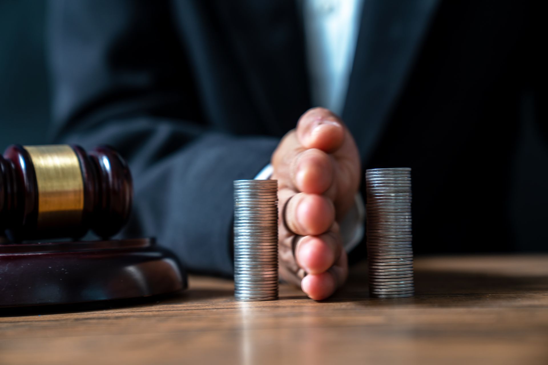 Lawyer's hand holding coins on a pile of coins.
