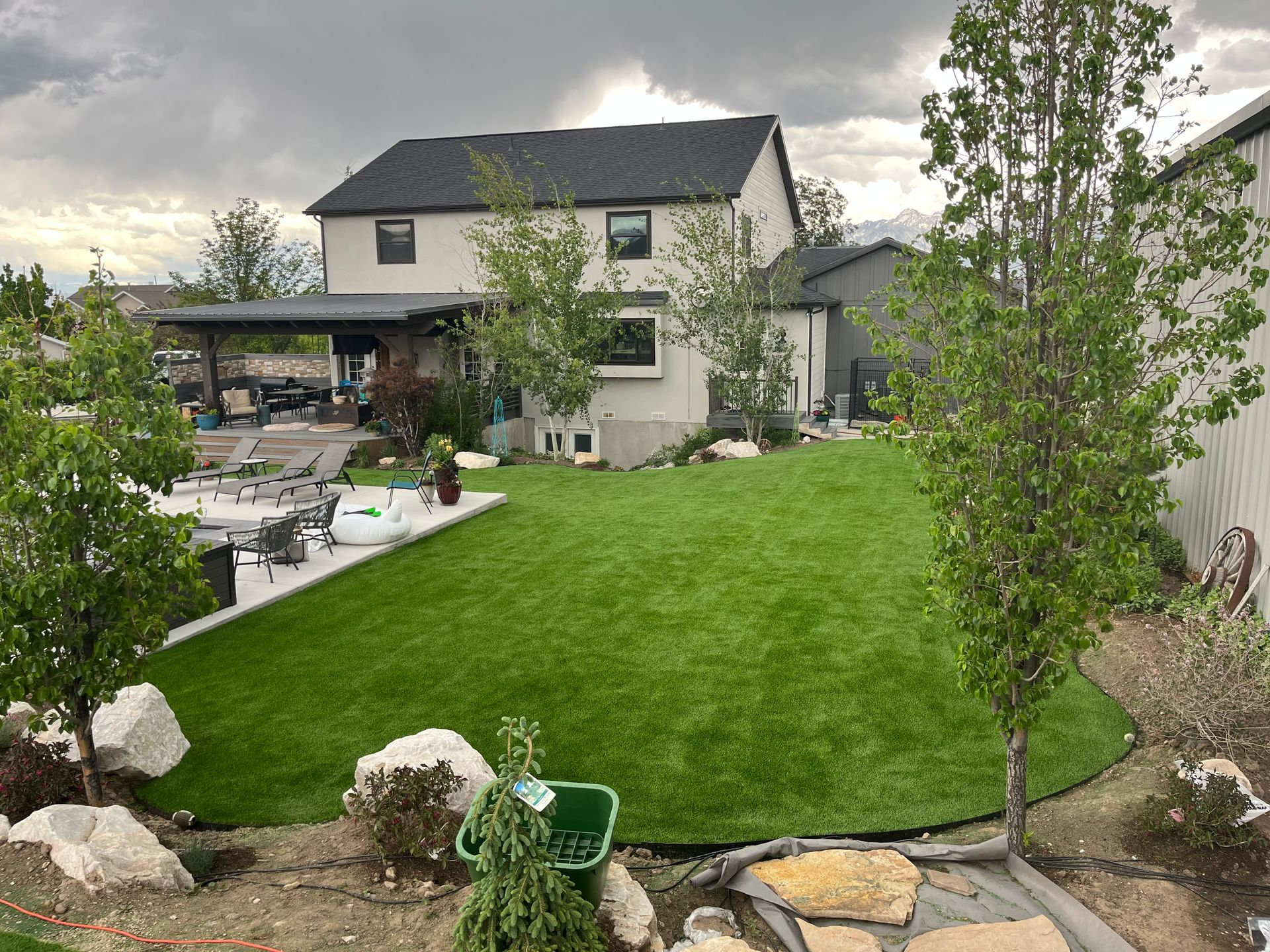 Green artificial turf lawn enclosed by white fence under a bright blue sky.