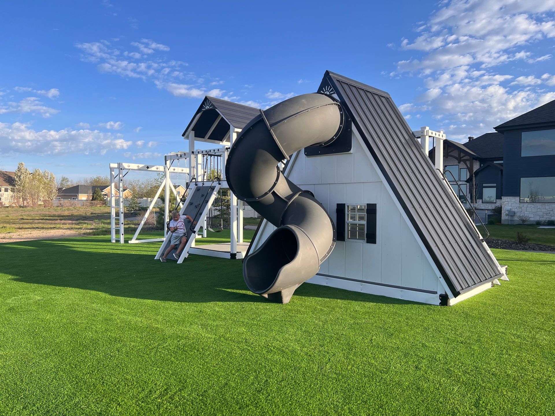 A house with green lawn and gravel walkway. A person walks in front.