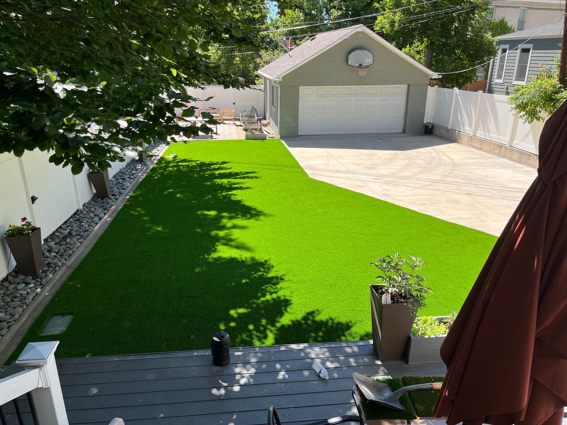 Backyard with green turf, a garage, and a concrete driveway.