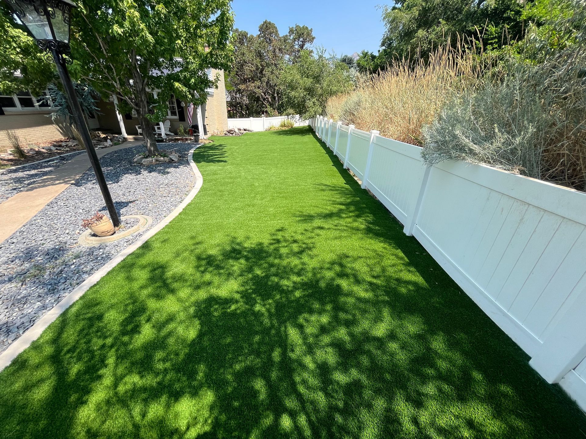 A house with a concrete driveway, gravel path, and a patch of green grass; mountains in the background.