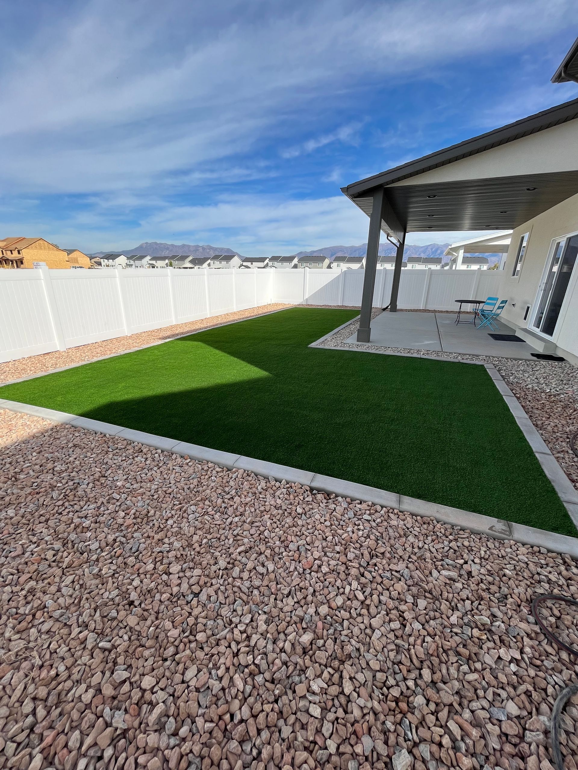 Construction of a backyard play structure on artificial turf with blue sky and a fence.