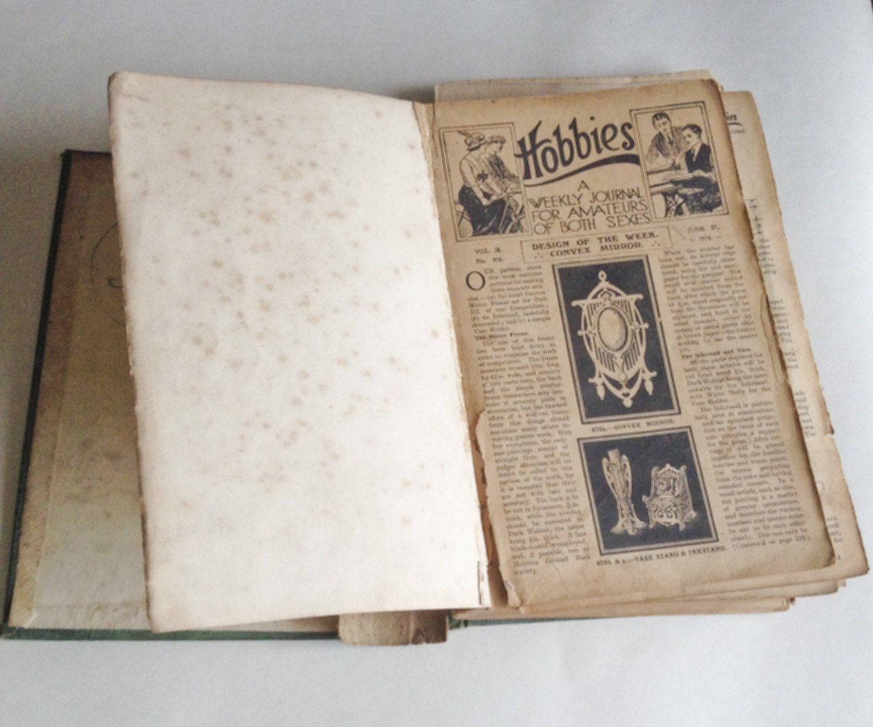 The image shows the damaged book open and the first page has foxing which means the page is speckled with brown mould. The next page has writing and reads Hobbies a weekly journal for amateurs of both Sexes. The book is vintage and old.