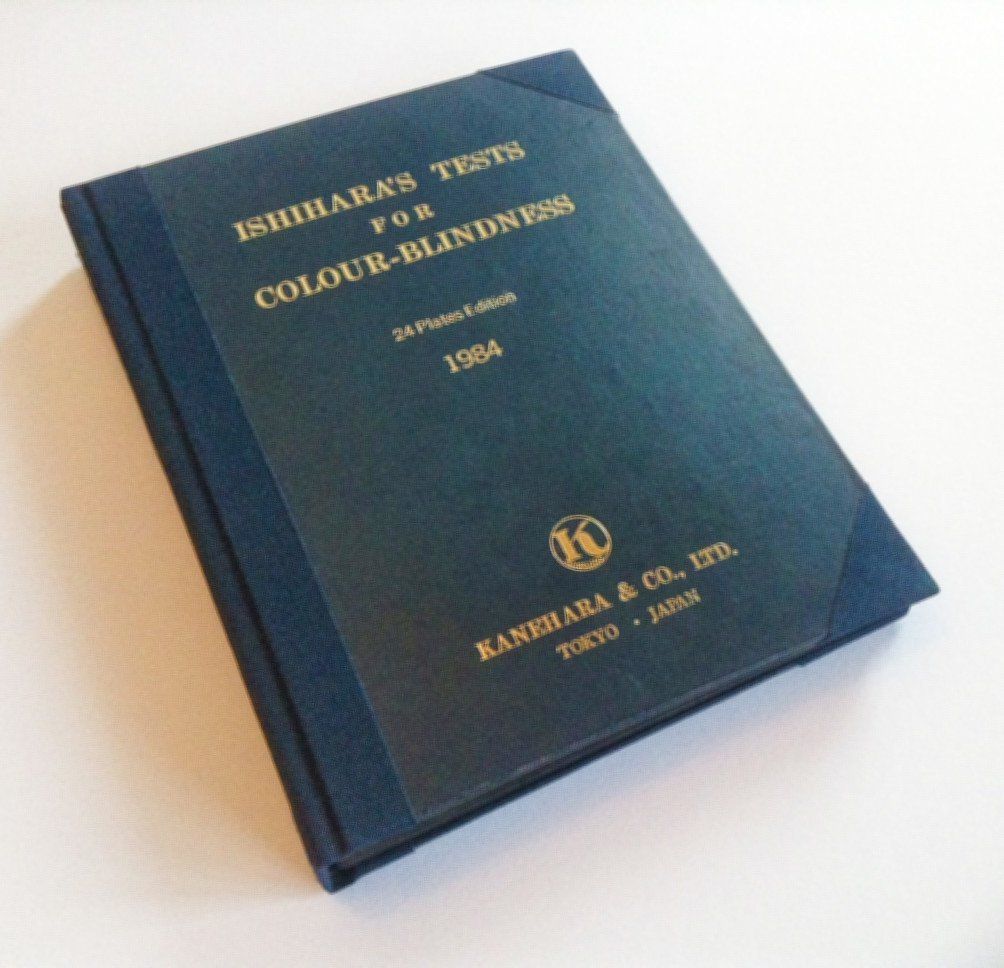 The image shows the dark blue book repaired and laid face up with the front cover visible on the table. The spine and hinges and corners of the covers have all been repaired with a dark blue book cloth to match the book.