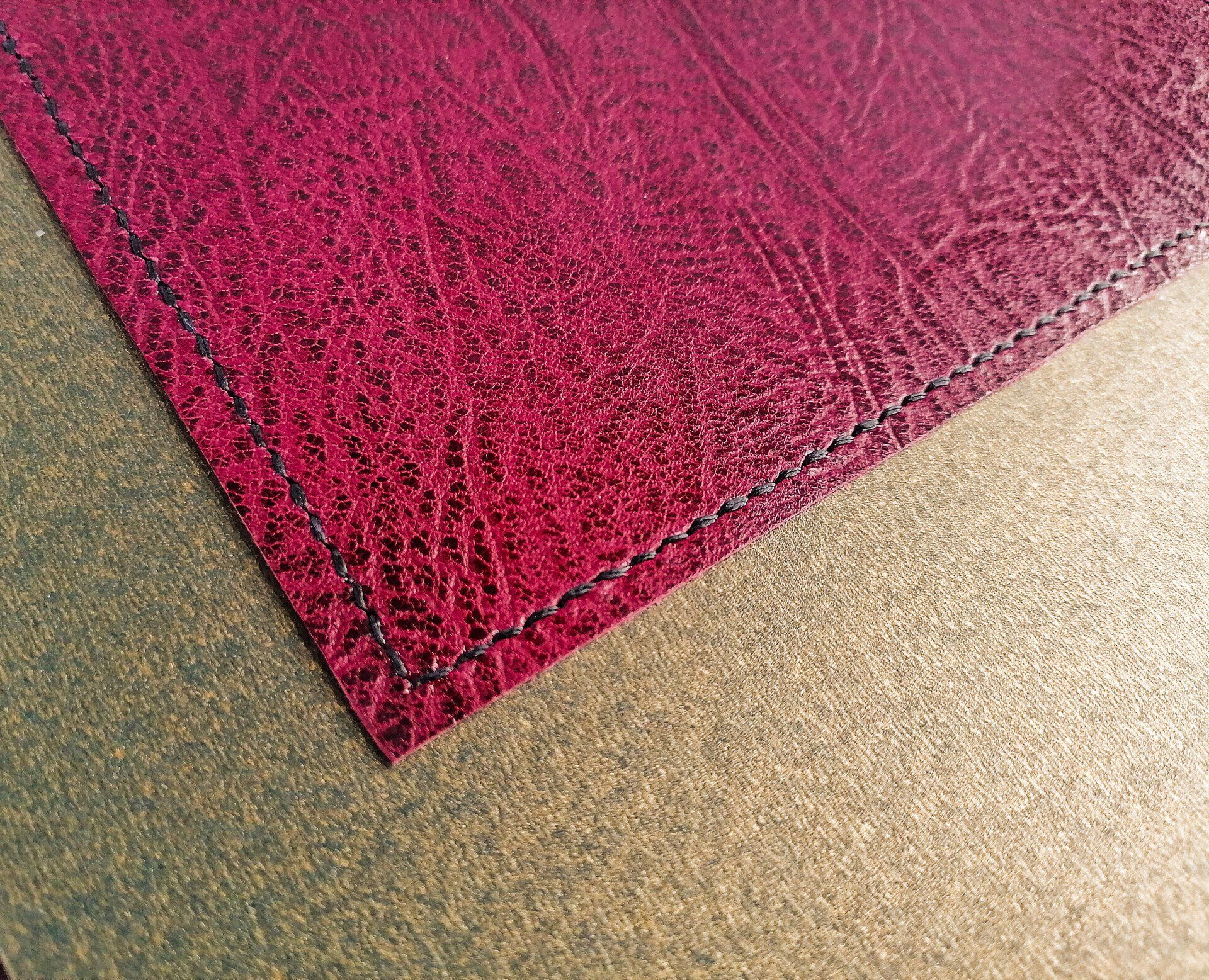 The image shows a close up of the internal maroon coloured leather pocket on the front cover. It has been stitched to the album by hand using black linen twine. This is to hold the front cover photo.