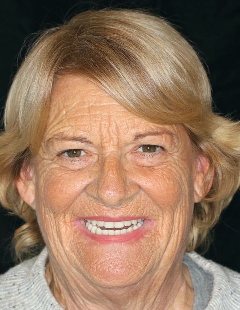 A close up of an older woman 's face with a smile on her face.