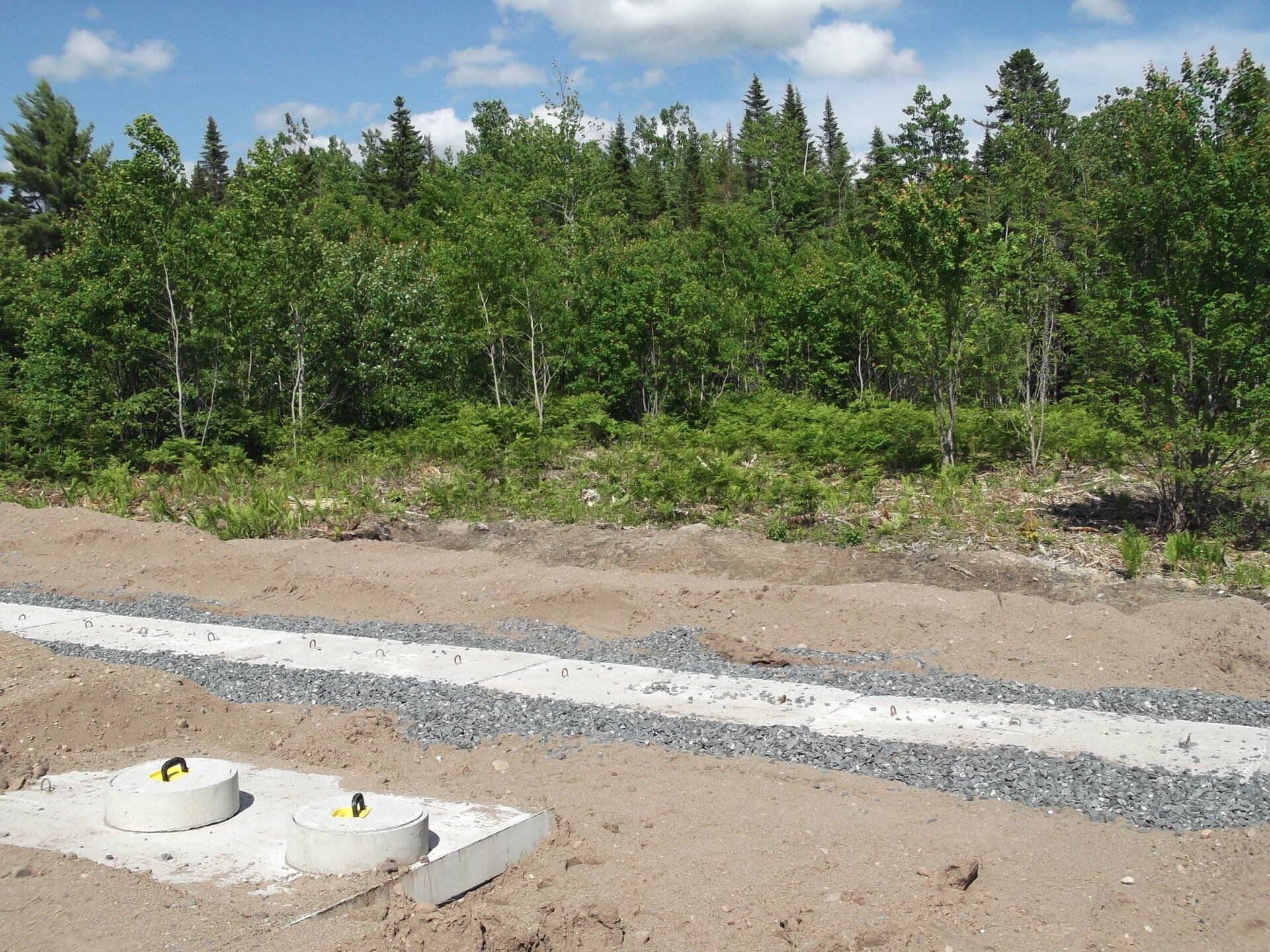 A concrete block in the middle of a dirt field with trees in the background
