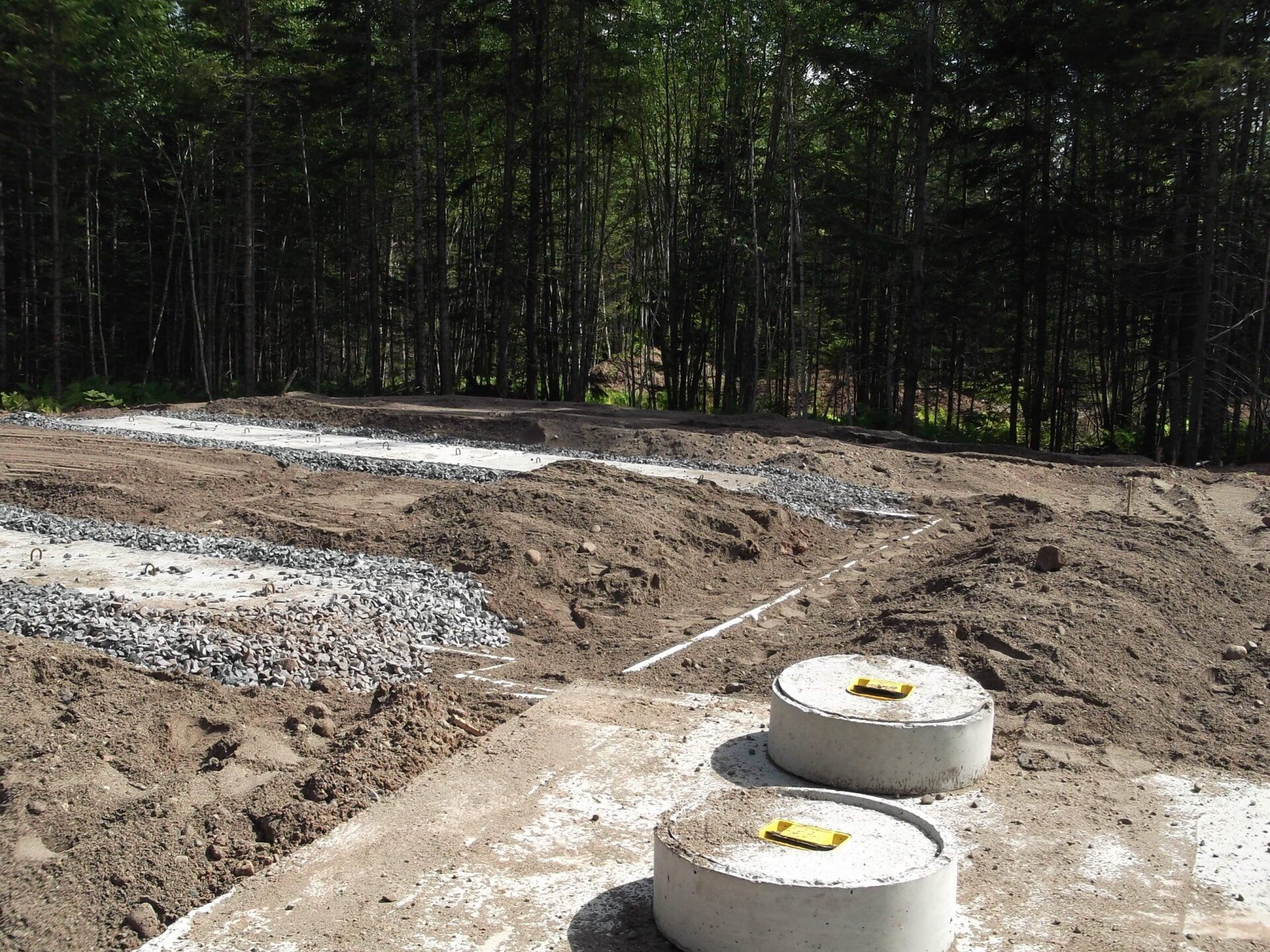 A concrete block with a yellow sticker on it sits in the middle of a dirt field.
