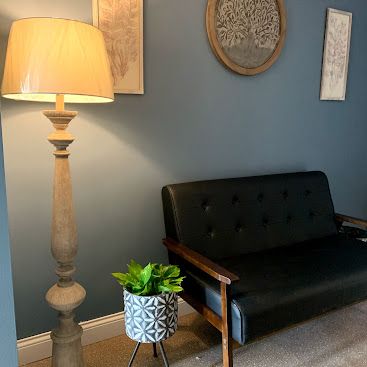 A living room with a couch , lamp , and potted plant.