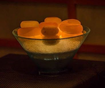 A glass bowl filled with orange ice cubes is sitting on a table.