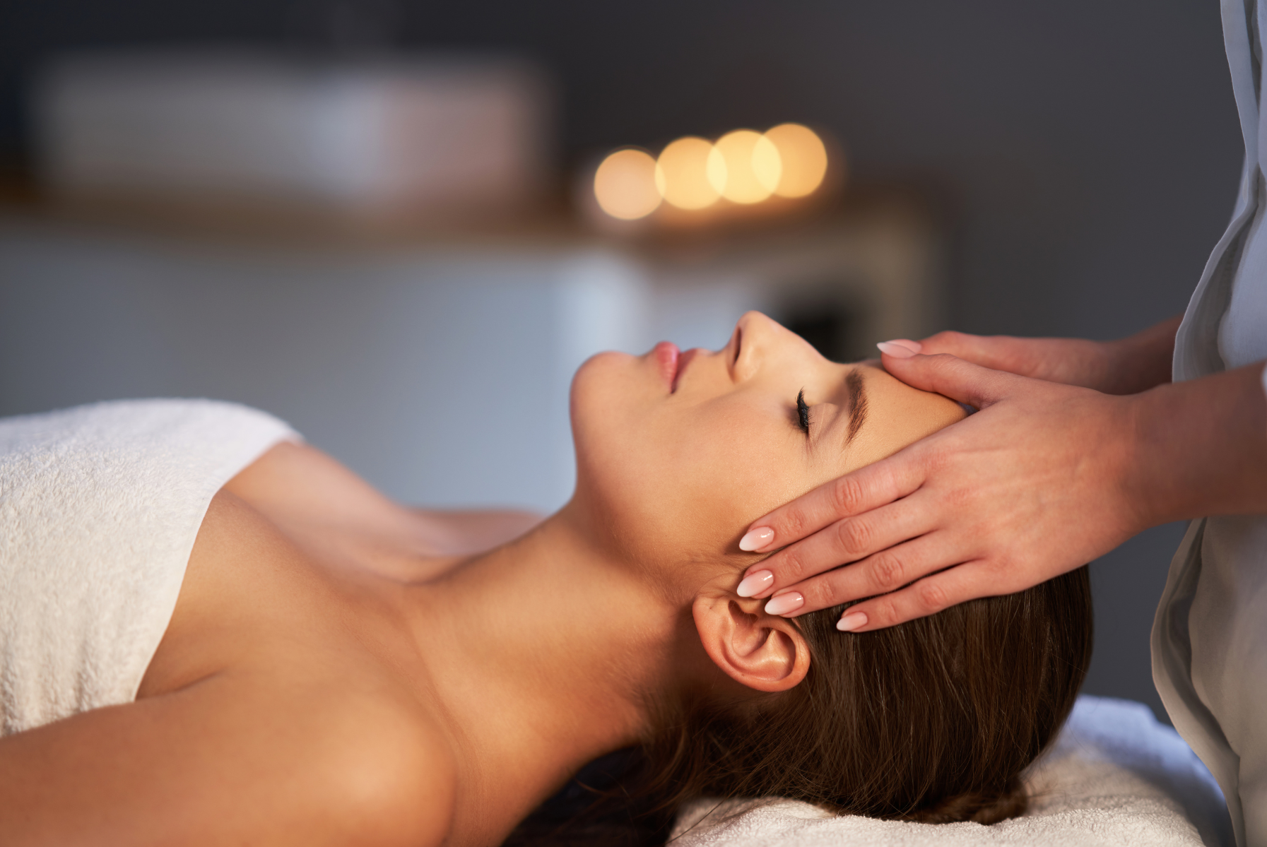 A woman is getting a head massage at a spa.