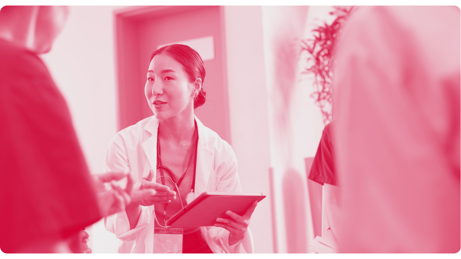 Woman smiling in a business meeting, wearing a blazer, with colleagues in the background.