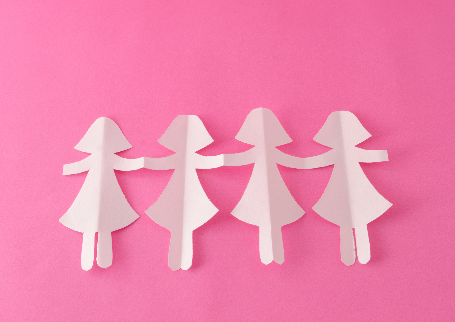 Four white paper figures holding hands on a pink background.