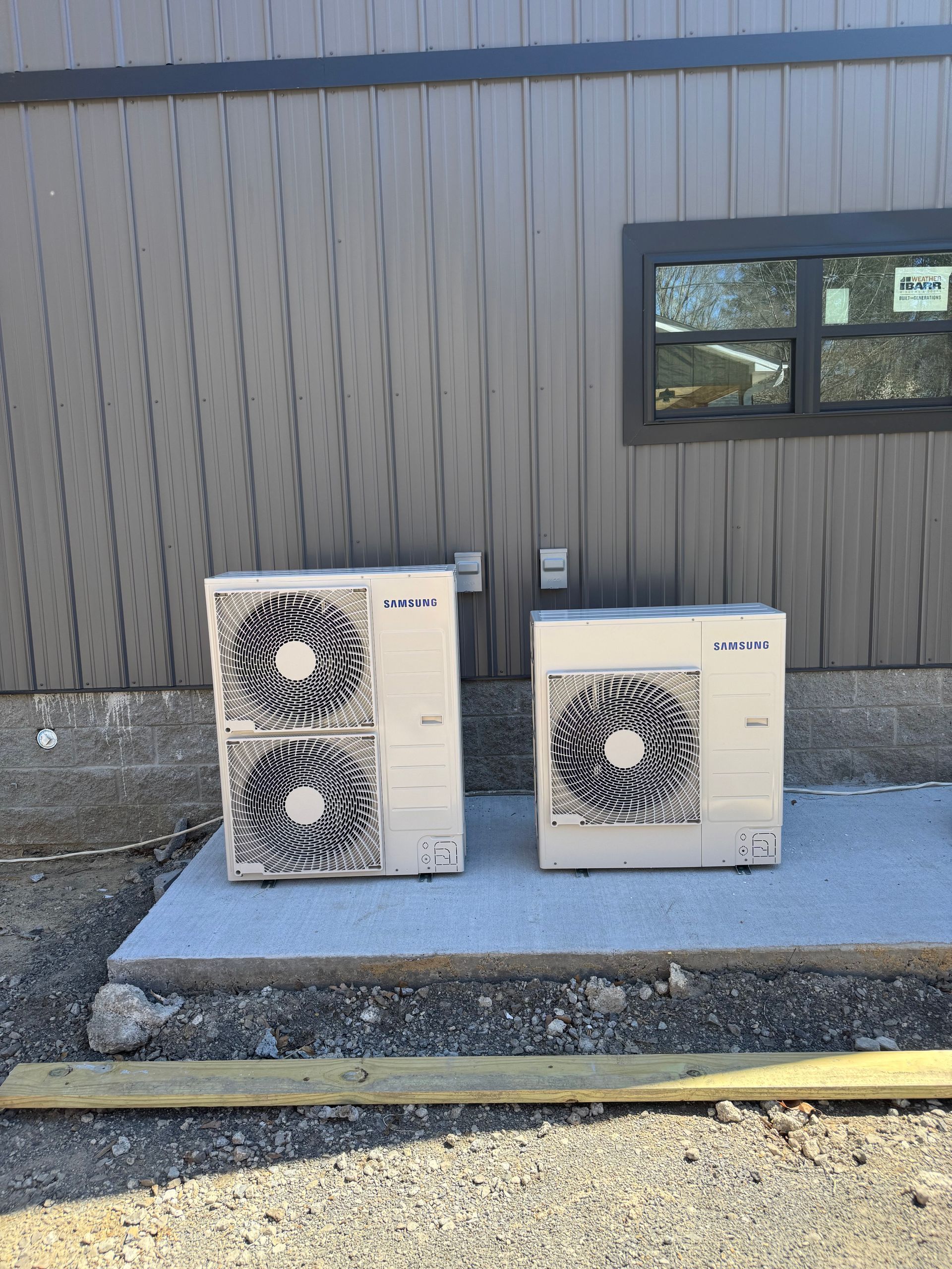 Two air conditioners are sitting outside of a building.