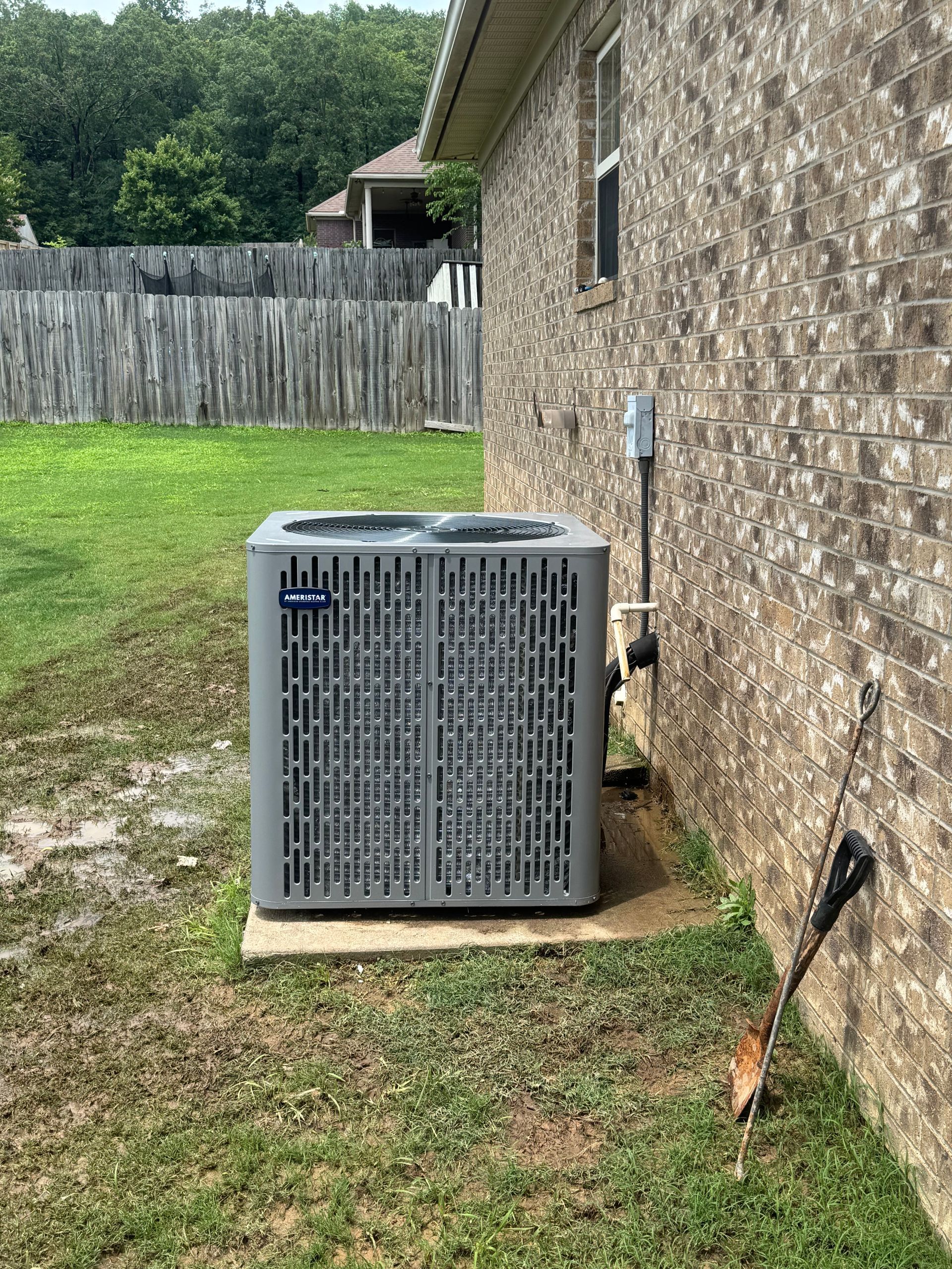 An air conditioner is sitting on the side of a brick house.