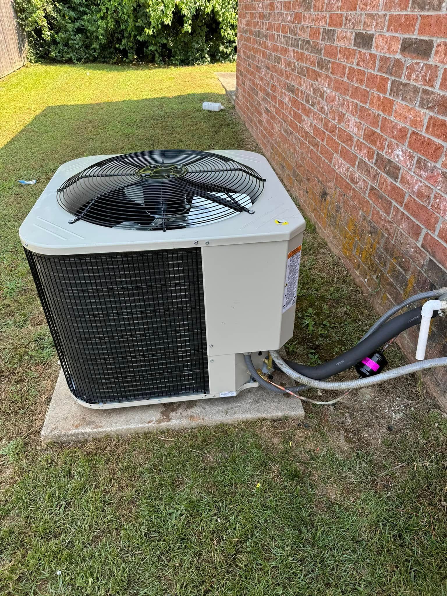 An air conditioner is sitting on the side of a brick building.