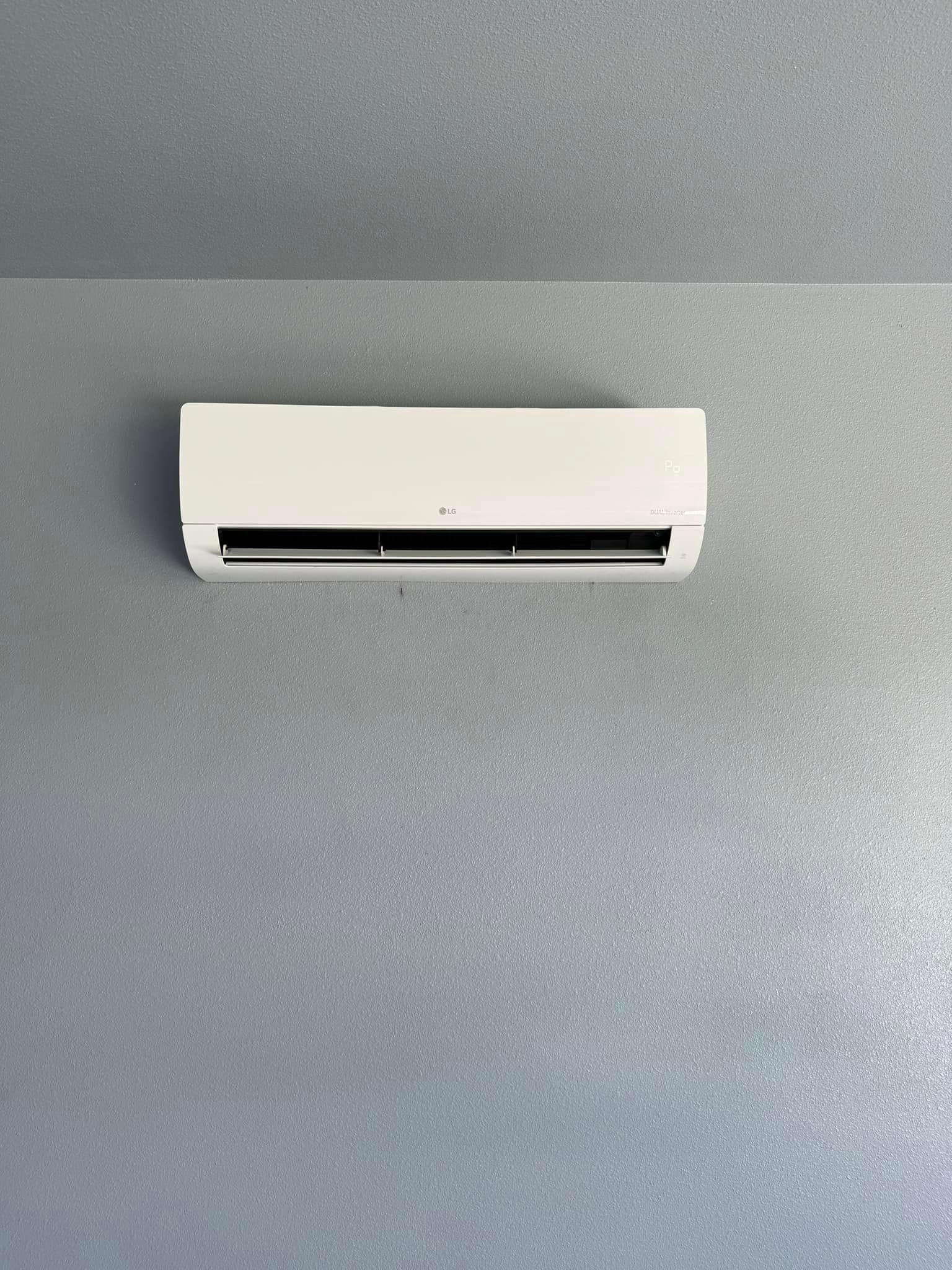 A white air conditioner is hanging on a gray wall.