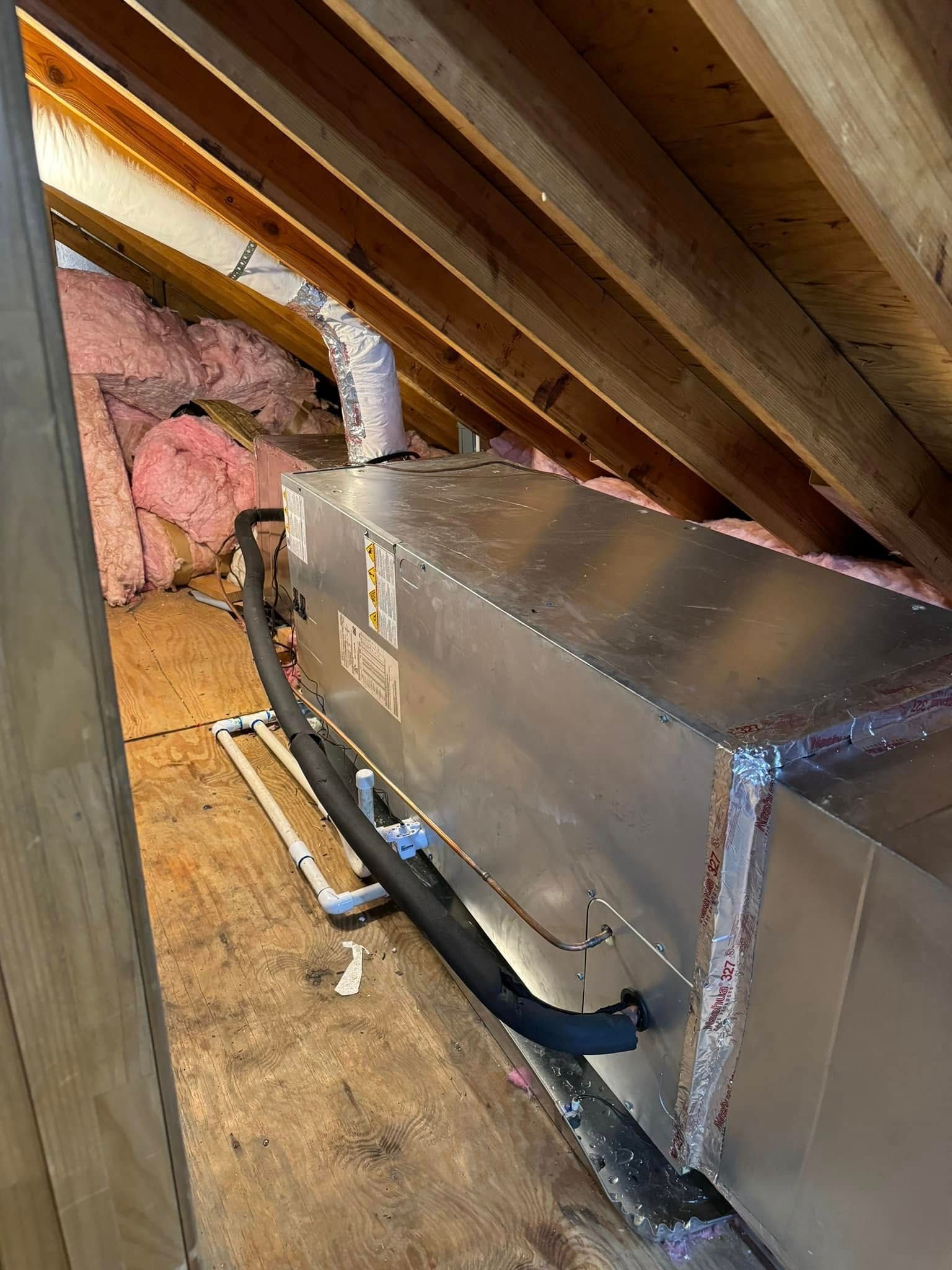An air conditioner is sitting in the attic of a house.