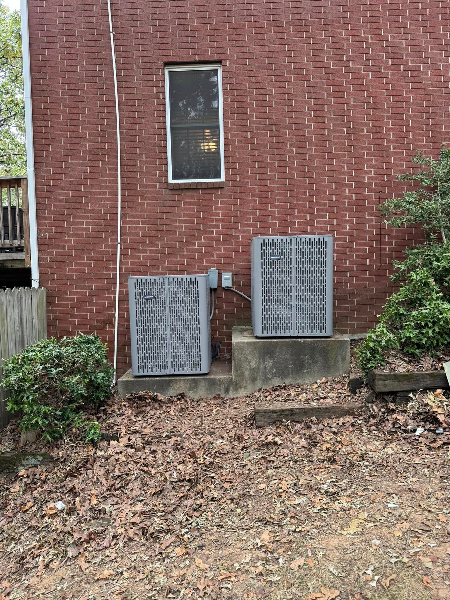 There are two air conditioners on the side of a brick building.