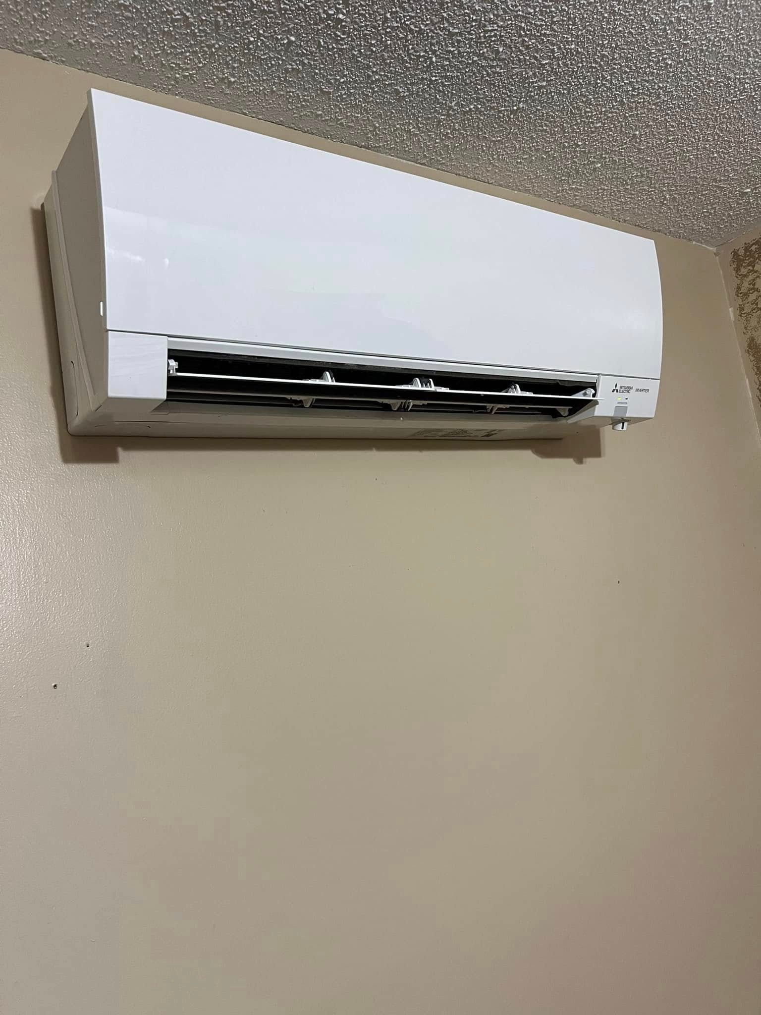 A white air conditioner is hanging on a wall in a room.