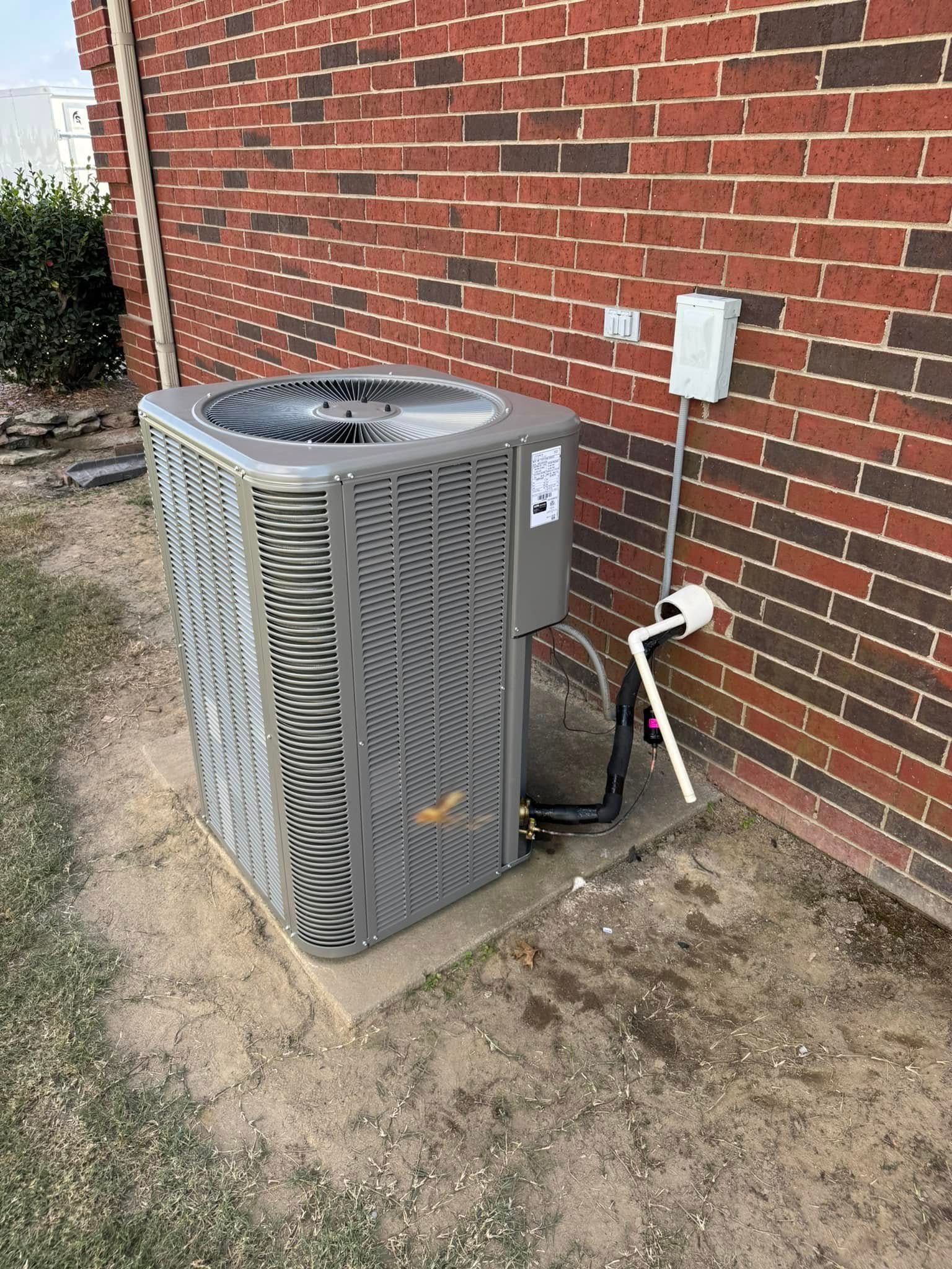 An air conditioner is sitting on the side of a brick building.