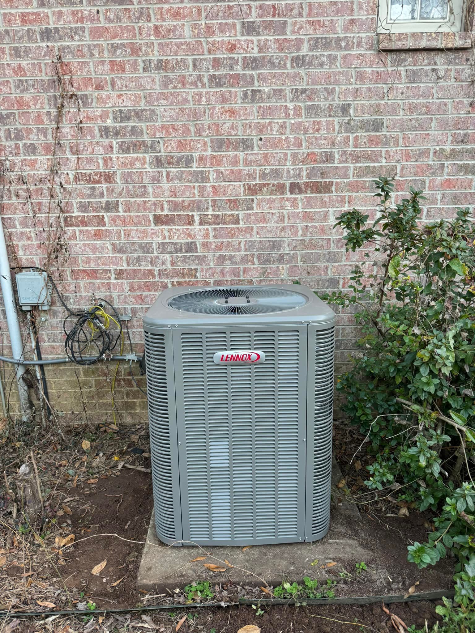 An air conditioner is sitting on the side of a brick building.