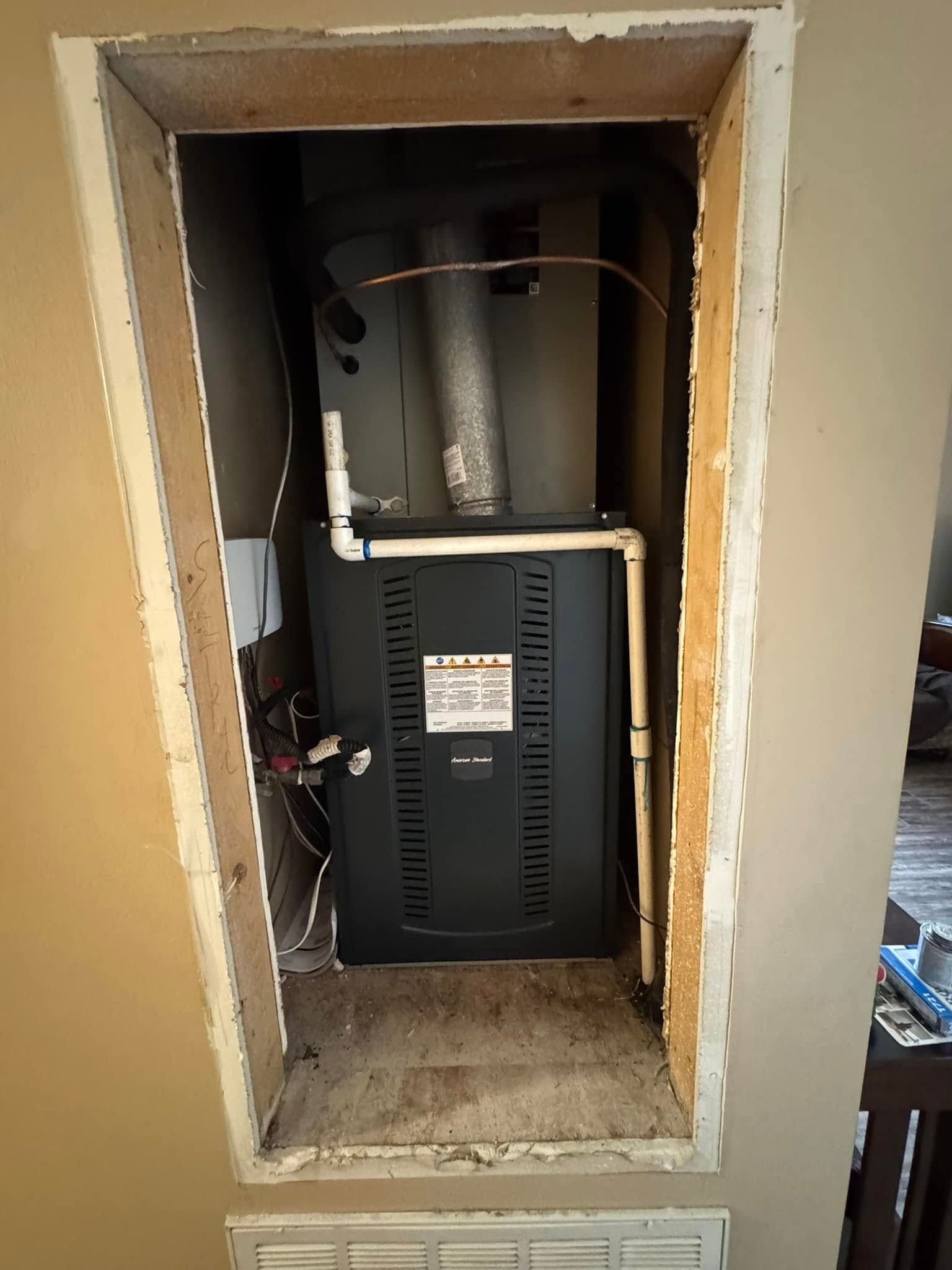 An air conditioner is sitting inside of a wall in a room.